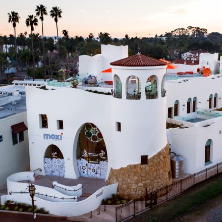 A contemporary building featuring a white roof and a serene pool, showcasing modern architectural design.