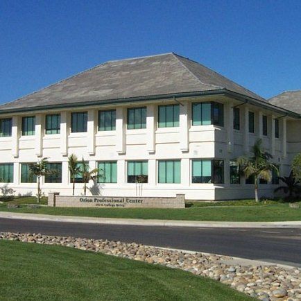 A white building stands prominently against a clear blue sky, showcasing its clean and modern architectural design.